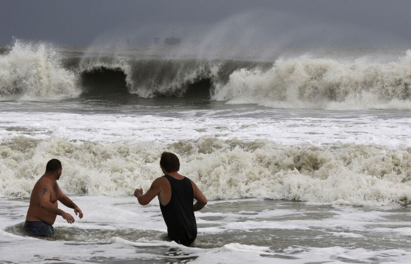 John Cunningham, left, and Hunter Shows, right, watch the waves crash from Tropical Storm Gordon on Tuesday, Sept. 4, 2018, in Dauphin Island, Ala. (AP Photo/Dan Anderson)