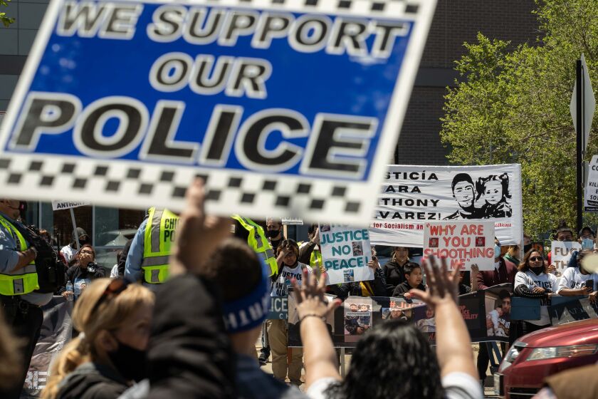 Protesters demand justice for Anthony Alvarez as police supporters gather on the opposite side of Milwaukee Avenue Saturday in front of the Jefferson Park district police station.