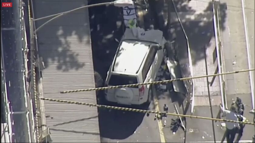 In this photo made video from the Australian Broadcasting Corp., a white SUV vehicle is stopped after allegedly striking pedestrians, Thursday, Dec. 21, 20217, in Melbourne, Australia. Local media say over a dozen people have been injured after a car drov