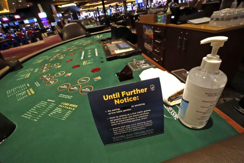 Hand sanitizer and a card explaining there will be no smoking or eating at gaming tables await the return of gamblers at Rivers Casino in Pittsburgh on Monday.