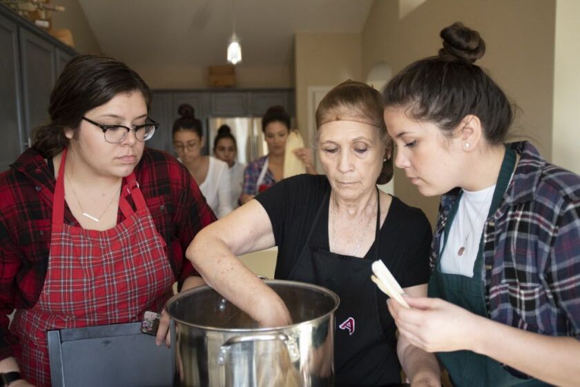Evelyn Sandoval and Mariana Aldaba, two of Elodia Esquinca’s granddaughters, crowd around her as she places prepared tamales in a pot in on Dec. 16, 2018. | Colin Boyle/Sun-Times