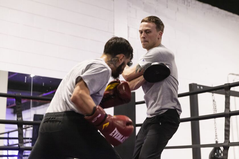 Jordan Gearey, 27, a case manager with a Puerto Rican Cultural Center violence prevention program (right) helps train Christian Colunga, 24, (left) at The Barracks Boxing Club on the Northwest Side.