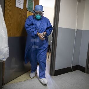 A nurse takes her gloves off as she walks out of a patient’s room after the 56-year-old woman suffering from COVID-19 prompted a rapid response, meaning respiratory or cardiac arrest, at Roseland Community Hospital on the Far South Side, Tuesday afternoon, April 28, 2020.