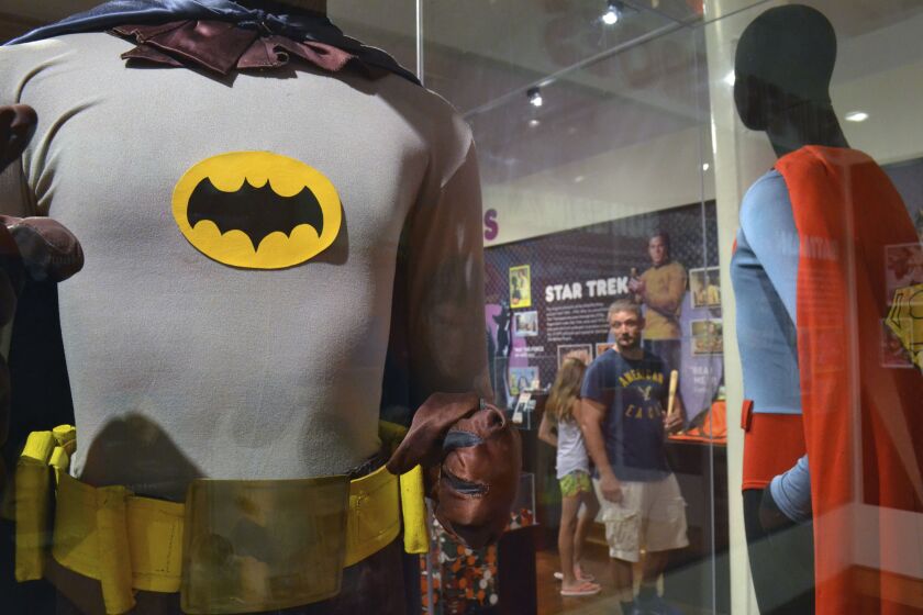 A Batman costume worn by Adam West in the 1960s television show is shown on display in 2015 next to a Superman costume worn by Christopher Reeve in “Superman IV” at the Louisville Slugger Museum in Louisville, Ky. | Dylan Lovan/Associated Press