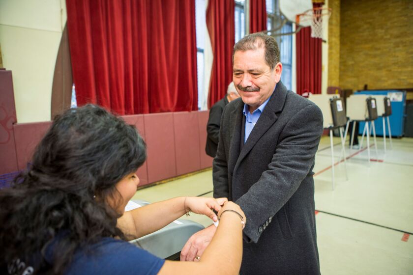 Jesus “Chuy” Garcia gets a wristband to show he voted at his polling place Tuesday at the Daniel J. Corkery Elementary School. | James Foster/For the Sun-Times