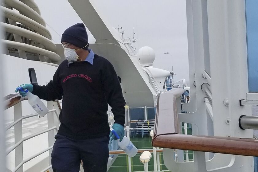 A cruise ship worker cleans a railing on the Grand Princess on Thursday.