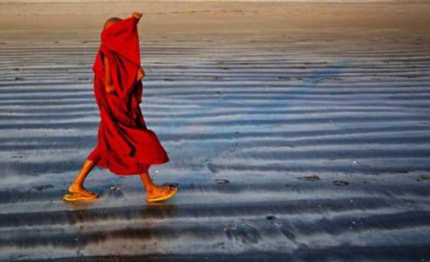 A novice Buddhist monk rearranges his robe as he walks on the beach in Ngwe Saung in western Ayeyarwady division, Myanmar Saturday, Feb. 7, 2015. (AP Photo/Gemunu Amarasinghe) ORG XMIT: XGA104