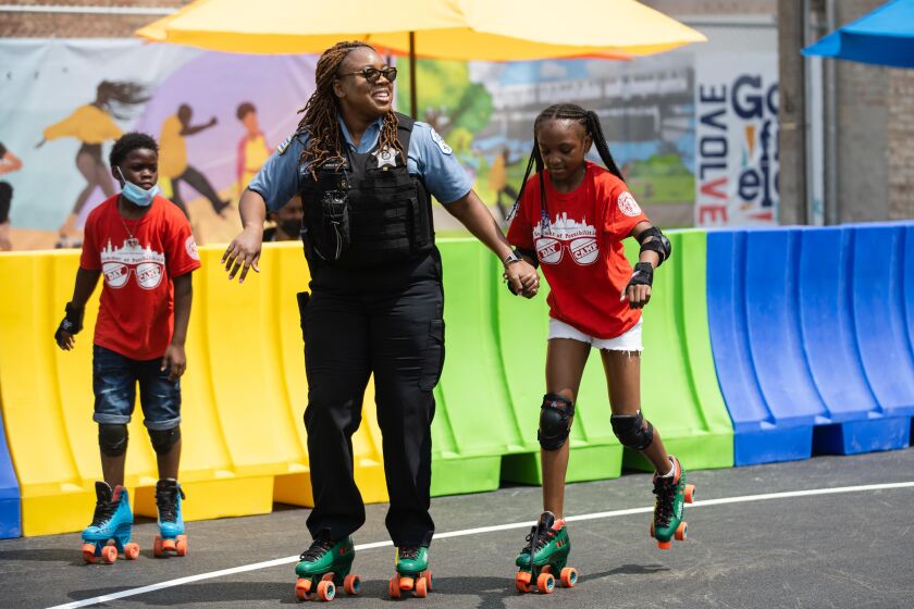 A police officer skates with a kid at the Garfield Park Community Plaza and Outdoor Roller Rink during its opening day in the West Garfield Park neighborhood, Friday afternoon, July 23, 2021.