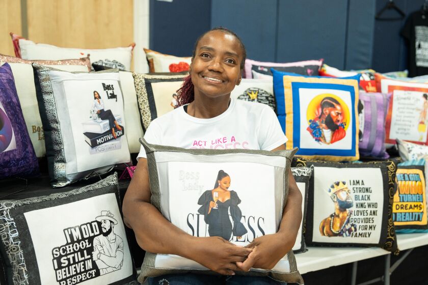 Linda Meekins, a project consultant and designer at Emma & Marie Designer Projects, shows off her pillows for sale on Saturday.