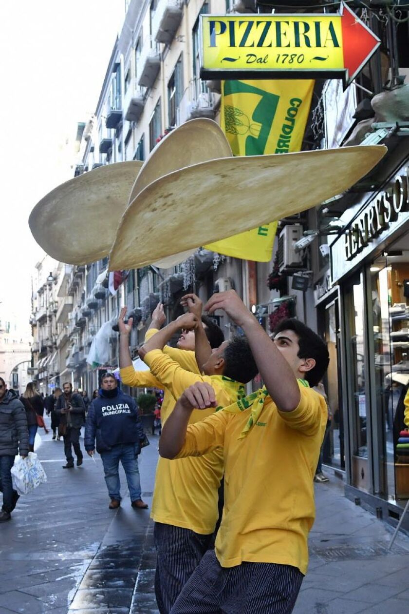 Members of the Pizzaioli Acrobats Coldiretti perform “twirling” pizza to celebrate the Unesco decision to make the art of Neapolitan “Pizzaiuolo” an “intangible heritage”, on December 7, 2017 in Naples. | TIZIANA FABI/AFP/Getty Images