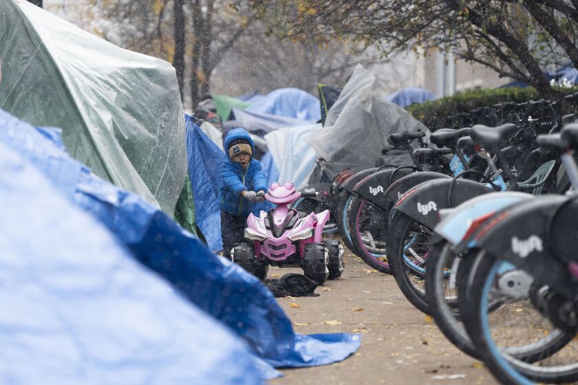 José Leonardo Urribarri, an asylum seeker, pushes a toy vehicle outside the 18th District police station in River North, where he and his family are temporarily staying, as the first snowfall of the season hits the Chicago area, Tuesday, Oct. 31.