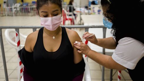 A healthcare worker administers an AstraZeneca booster shot for COVID 19 at a vaccination center in Guatemala City, Tuesday, March 1, 2022.