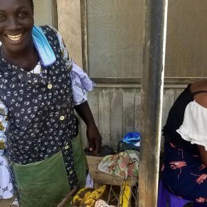 A woman selling grilled plantain smiles.