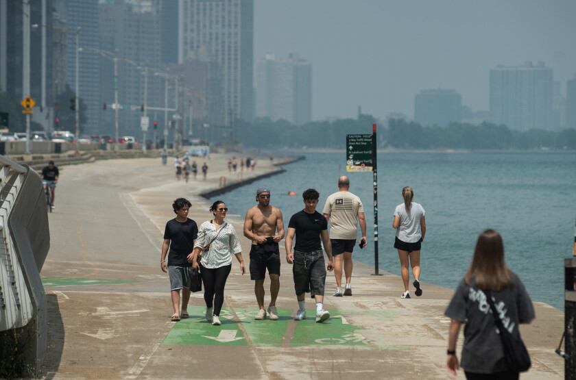 Few people walk on the lakefront and swim in Lake Michigan at Ohio Street Beach in Streeterville as the Chicago skyline is obscured by air pollution driven by the wildfires in Canada on Friday.