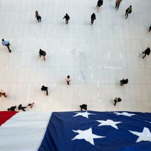People walk under an American flag inside the Oculus, part of the World Trade Center transportation hub, on the anniversary of 9/11 terrorist attacks in New York on Tuesday, Sept. 11, 2018. | AP Photo