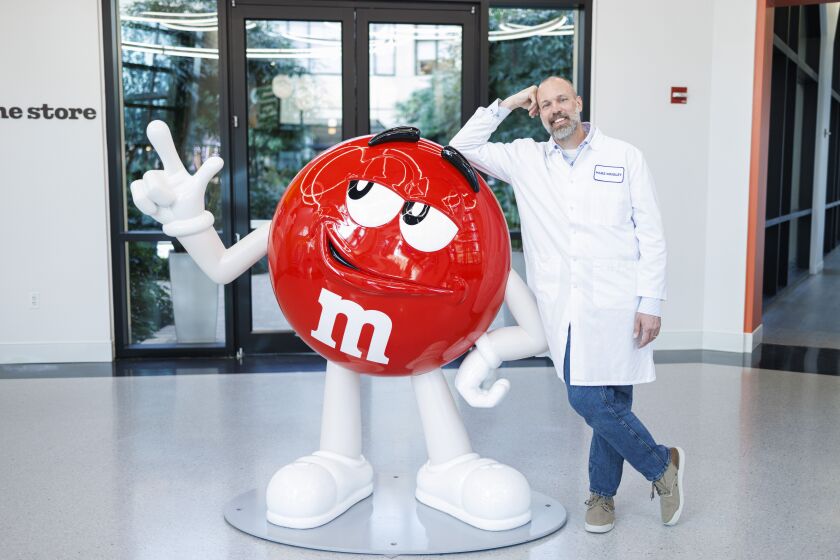 Mars Chocolate scientist Matthew Kradenpoth leans against a statue of the Red M&M in the Mars Wrigley global headquarters at Goose Island.