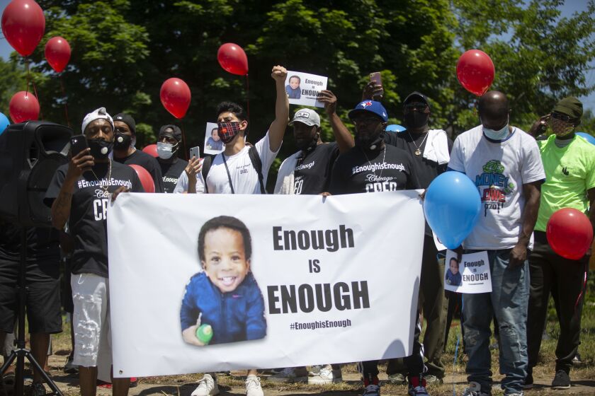 Friends and family hold signs and balloons for support during a vigil for Sincere A. Gaston in Englewood on Wednesday.