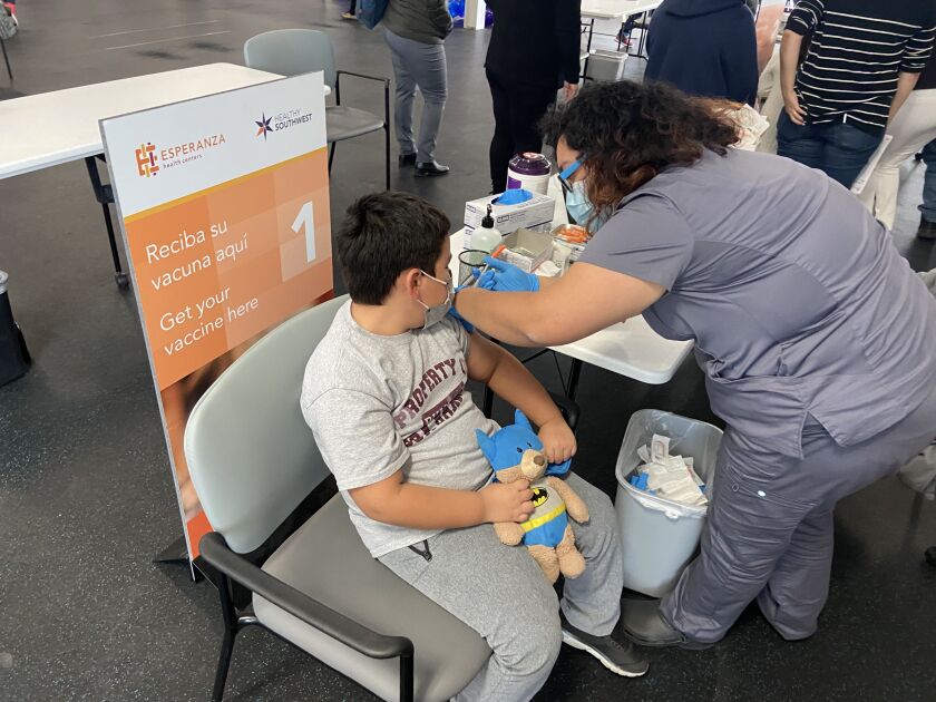 Benicio Decker holds tight to his favorite stuffed animal, “Bat Bear,” as medical assistant Rachel Blancas gives him a COVID vaccine at a mass clinic sponsored by Esperanza Health Centers on the Southwest Side.