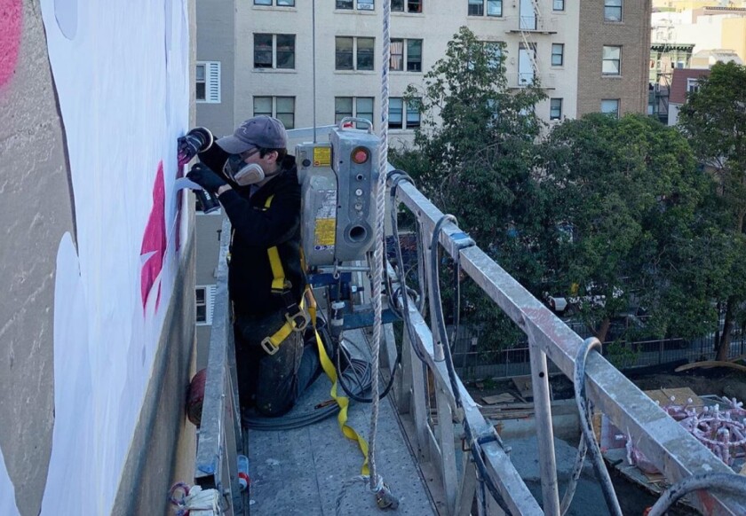 The artist by “fnnch” working on a mural earlier this year in San Francisco.
