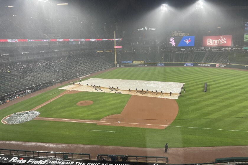 Crews pull the tarp on the field late Tuesday during the Sox' game against the Blue Jays.