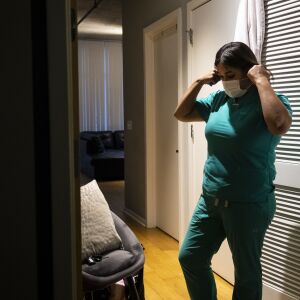 Nurse practitioner Capri Reese removes her face mask, sanitizes her shoes and put her scrubs in the washing machine before immediately showering at her South Loop apartment after a 12-hour shift at Roseland Community Hospital, where three patients suffering from COVID-19 died, Tuesday afternoon, April 28, 2020.