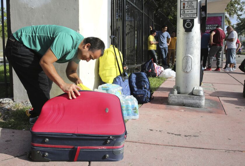 Leonel Geronimo, stuffs food into his suitcase Friday as he and others wait for a bus in anticipation of Hurricane Irma in Miami Beach, Fla. Geronimo wants to get to a shelter off the beach, but is not sure what bus to take or which shelter to go. | Marta