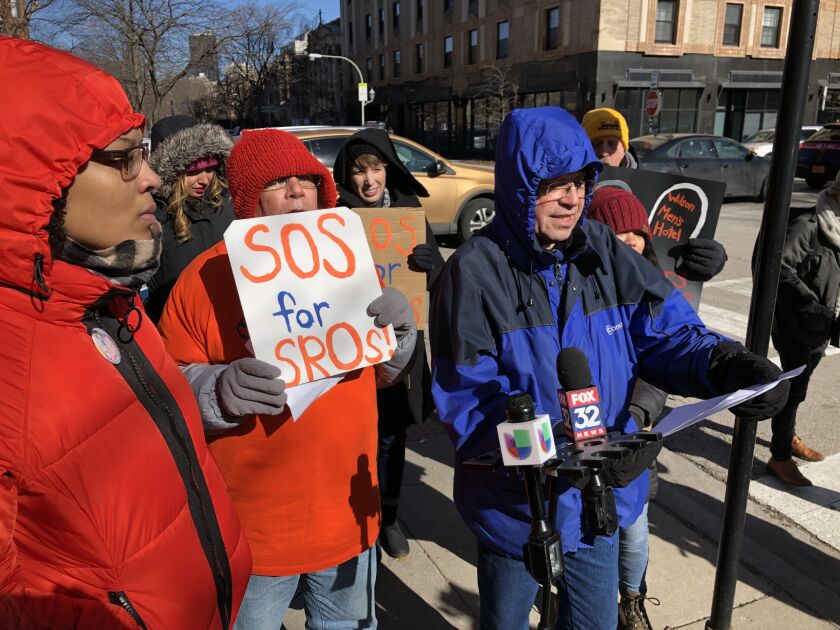 John Adams (in blue coat), a former resident of the now-closed Wilson Men’s Hotel, was among the speakers at a news conference Friday outside the Lorali, 1039 W. Lawrence Ave. Activists gathered in the frigid cold for the news conference to call attentio