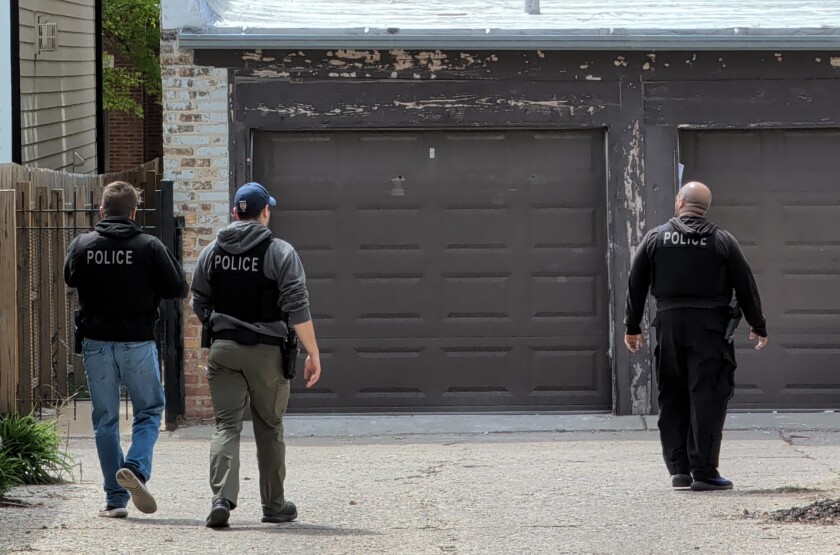 Officers inspect a backyard in the 2600 block of West Carmen Avenue.