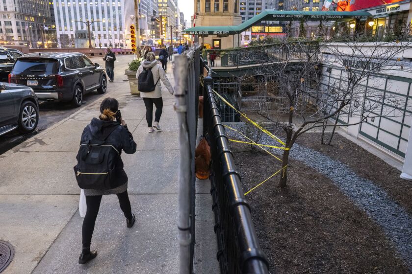 Pedestrians walk by the approximate location of an overnight crash that killed a 56-year-old woman who was walking at the time in the 300 block of North State Street outside Marina City in River North, Thursday, Dec. 7.