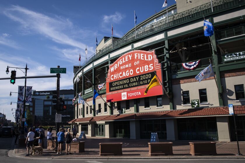 Fans take selfies outside Wrigley Field shortly before the start of the opening day game between the Chicago Cubs and the Milwaukee Brewers, Friday evening, July 24, 2020.