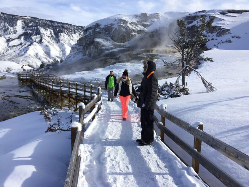 James Kristy and Ginger Lee of Palm Beach County, Fla., on the boardwalk at Yellowstone National Park’s Mammoth Hot Springs on Saturday. Visitors can still ride snowmobiles and snow coaches into Yellowstone National Park to gaze at the geysers and buffalo