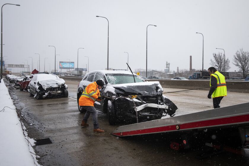S & T Automotive Towing and Repair workers tow a car from the scene of a massive pileup crash involving nearly 60 vehicles, sending more than a dozen people to hospitals, in the inbound lanes of the Kennedy Expressway near North Avenue, Wednesday morning, April 15, 2020.