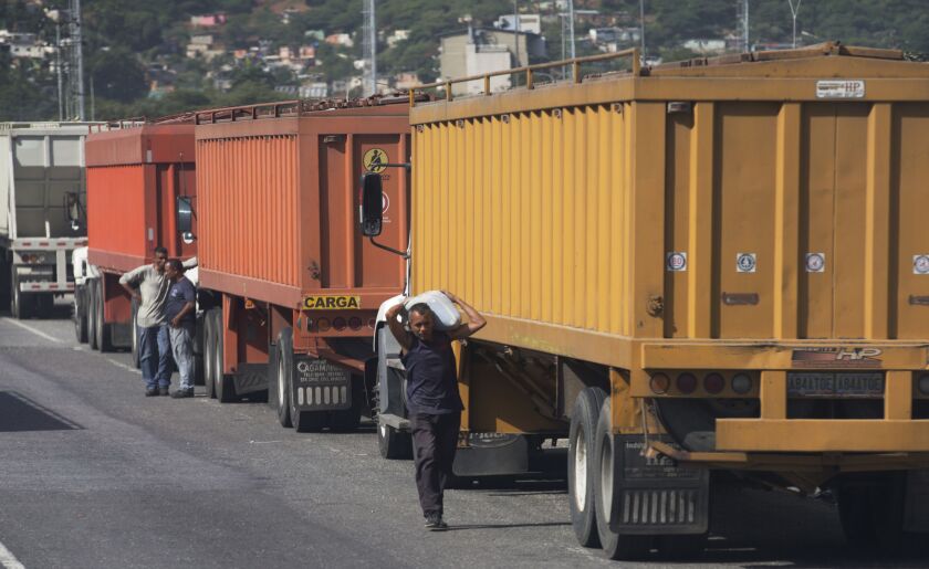 In this Jan. 23, 2018 photo, a man carries a sack of white corn he stole from grain-carrying trucks parked outside the port in Puerto Cabello, Venezuela. | AP photo
