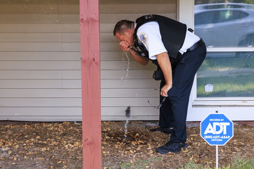 A member of the Chicago Police Department washes his face after being exposed to CS gas at the intersection of East 105th Street and South Avenue N in the East Side, Tuesday, Oct. 14, 2025. Protesters gathered as federal immigration enforcement agents awaited the removal of their vehicle involved in a crash during a pursuit.