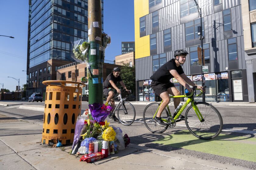 Cyclists ride by a memorial for Sam Bell, near the scene where Bell was struck and killed by a vehicle while riding his bike in the 700 block of North Milwaukee Avenue, Friday, Sept. 9.
