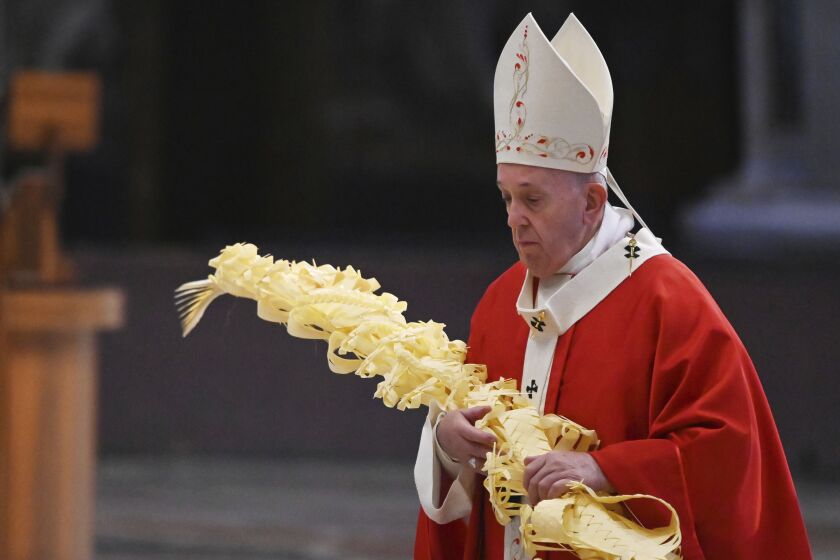Pope Francis holds a palm branch as he celebrates Palm Sunday Mass behind closed doors in St. Peter’s Basilica, at the Vatican, Sunday, April 5, 2020.