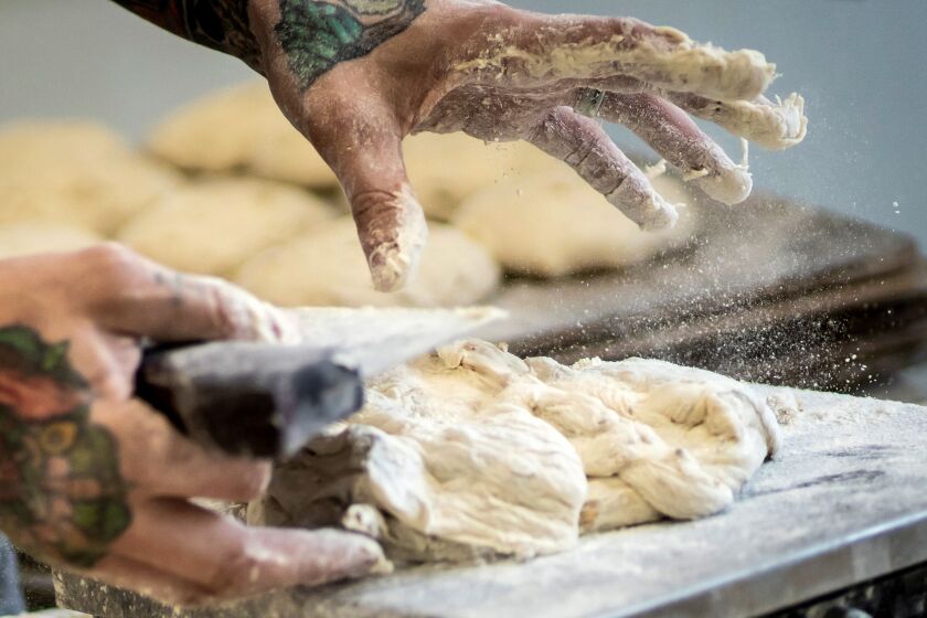 Chef Greg Wade portions honey-oat porridge dough in the kitchen at Publican Quality Bread.