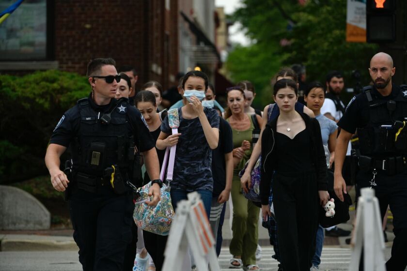 Policja w Highland Park eskortuje ludzi w poniedziałek po południu, którzy szukali bezpiecznego miejsca po tym, jak strzelec z karabinem o dużej mocy otworzył ogień kilka godzin wcześniej podczas parady Czwartego Lipca w Highland Park.