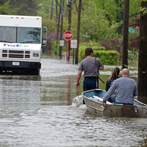 Triston Bakulinski pulls Lea Civitella and his dad Stanley Bakulinski along Hawthorne Lane in Des Plaines Monday as the neighborhood is flooded from Des Plaines River. They were hauling some pumping supplies to try and alleviate flooding in their homes.