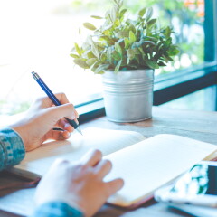 Woman hand writing on notepad with a pen in the office.