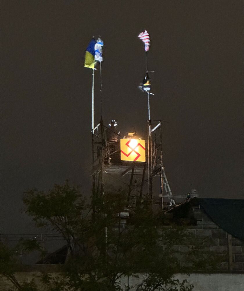 An illuminated swastika sign sits below several flags attached to makeshift scaffolding last month atop a Humboldt Park building in the the 4100 block of West Chicago Avenue.