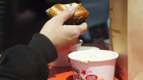 A customer holds a bagel at PopUp Bagels in Lincoln Park, Saturday, May 30, 2026.