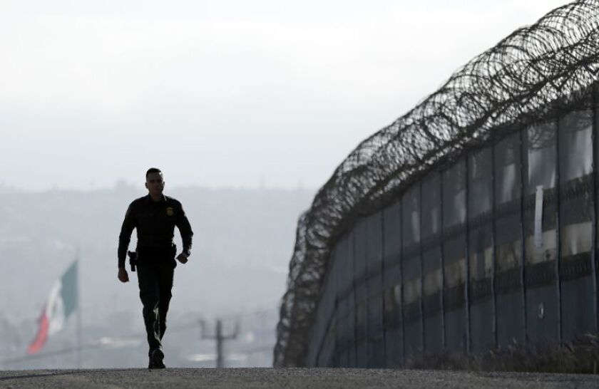 A Border Patrol agent walks near the secondary fence separating Tijuana, Mexico and San Diego. | Gregory Bull/AP file