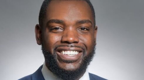 A Black man wearing a blue suit and tie with a pocket square.
