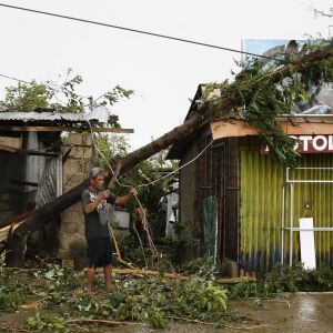 A resident cleans up pieces from a tree that was toppled by strong winds from Typhoon Mangkhut as it barreled across Tuguegarao city in Cagayan province, northeastern Philippines on Saturday, Sept. 15, 2018. The typhoon slammed into the Philippines northe