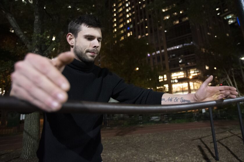 William Slotwinski puts his arms on a calisthenic bar at Lake Shore Park in the Streeterville neighborhood. On his left arm, a tattoo reads “Gimbarr Arte en Barras” (gimbarr, art on bars).