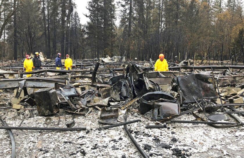Search team members move sheet metal to allow cadaver dogs to search beneath them for signs of human remains at a mobile home park in Paradise, Calif., Friday, Nov. 23, 2018. They said the mobile home park had already been hand searched, so they were re-e