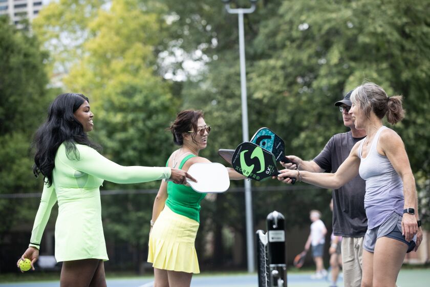 Tamara Jones (from left), Jeanie Mui, Doug Nebel and Becca Allistar tap their paddles after a pickleball game Aug. 1 at Roosevelt Park in Chicago.