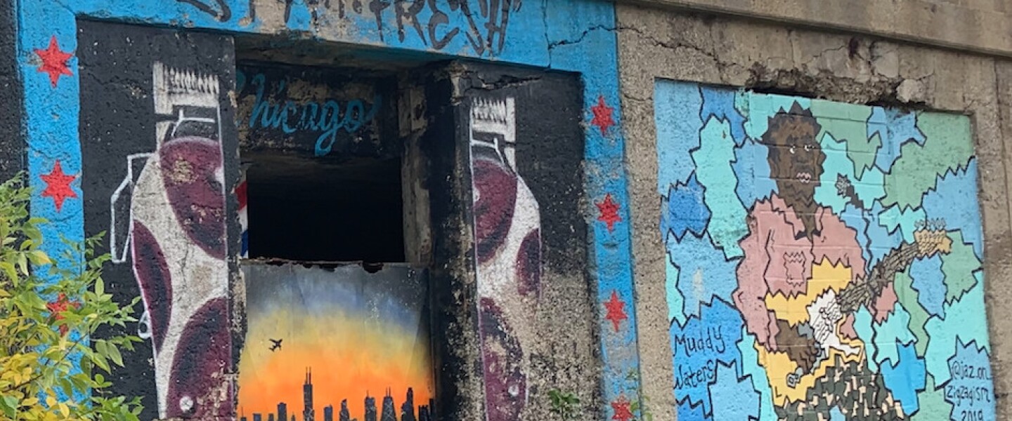 The painting at left was done by the South Side artist who goes by Viril the Mouse. Titled “Stay Fresh,” it includes the skyline flanked by hair clippers — as a nod to the “barber community.” He said, “Chicago’s all about being fresh, people like to look good type of thing.” At right is a mural by South Loop artist Jason Gaudette, 29, who goes by jaz.on.zigzagism for his artwork. The painting features late great Chicago bluesman Muddy Waters.