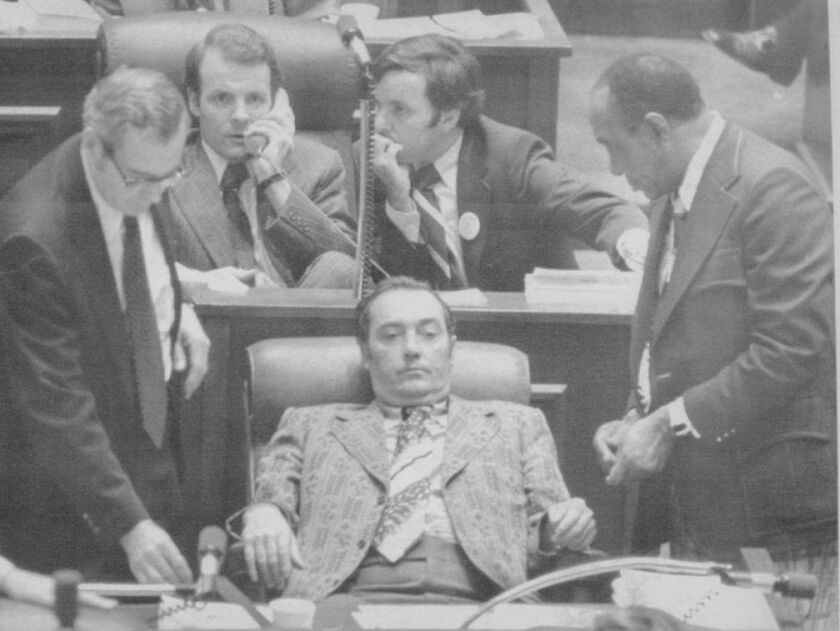 State Rep. Michael J. Madigan, top left, talks on the phone as state Sen. Richard M. Daley, kneels alongside during a meeting of Democratic leaders of both houses on the Illinois House of Representatives floor in Springfield in 1975. State Senate Presiden